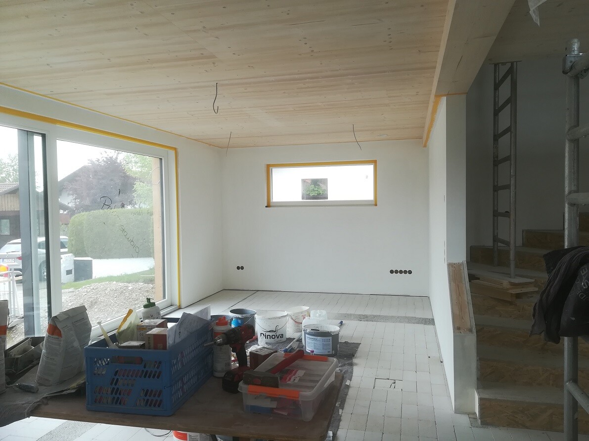 Renovierungsraum mit Holzdecke, großer Fensterfront, Bauwerkzeug-Tisch und Leiter.