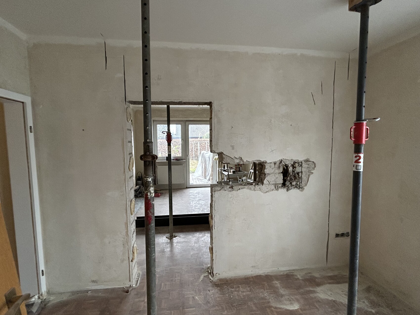 Renovierungsraum: Stahlstützen, grober Wanddurchbruch, unfertige Wände; Blick in angrenzenden Raum.