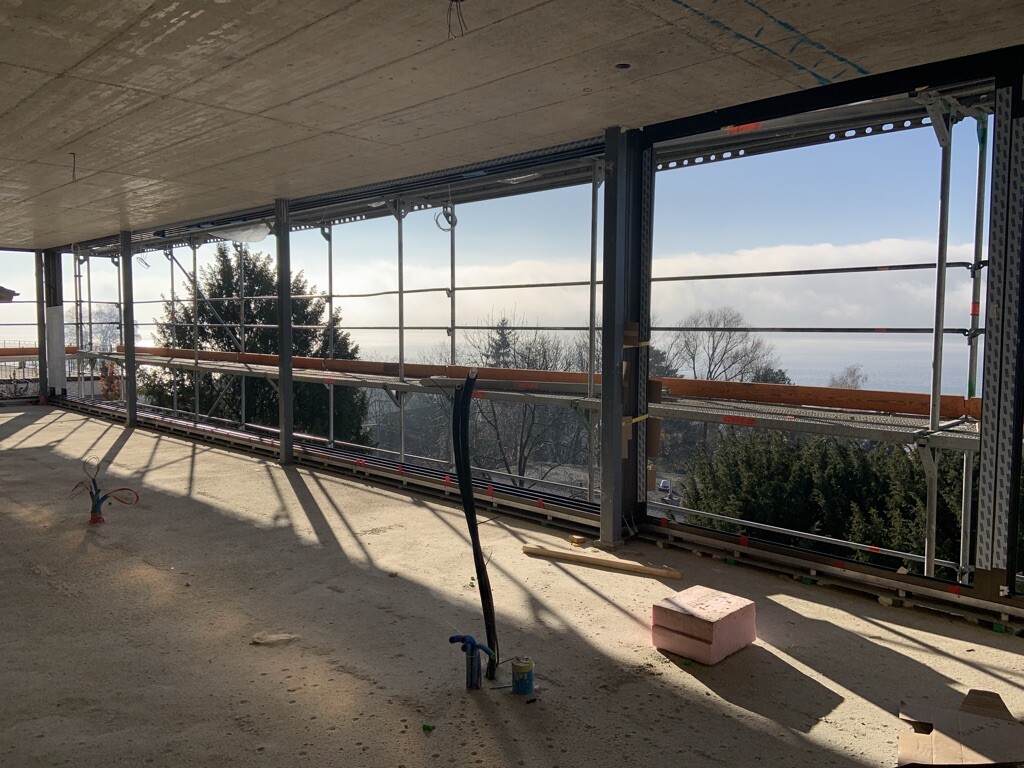 Unfertige Baustelle im Innenbereich mit Stahlrahmen, Geländern und Meerblick.