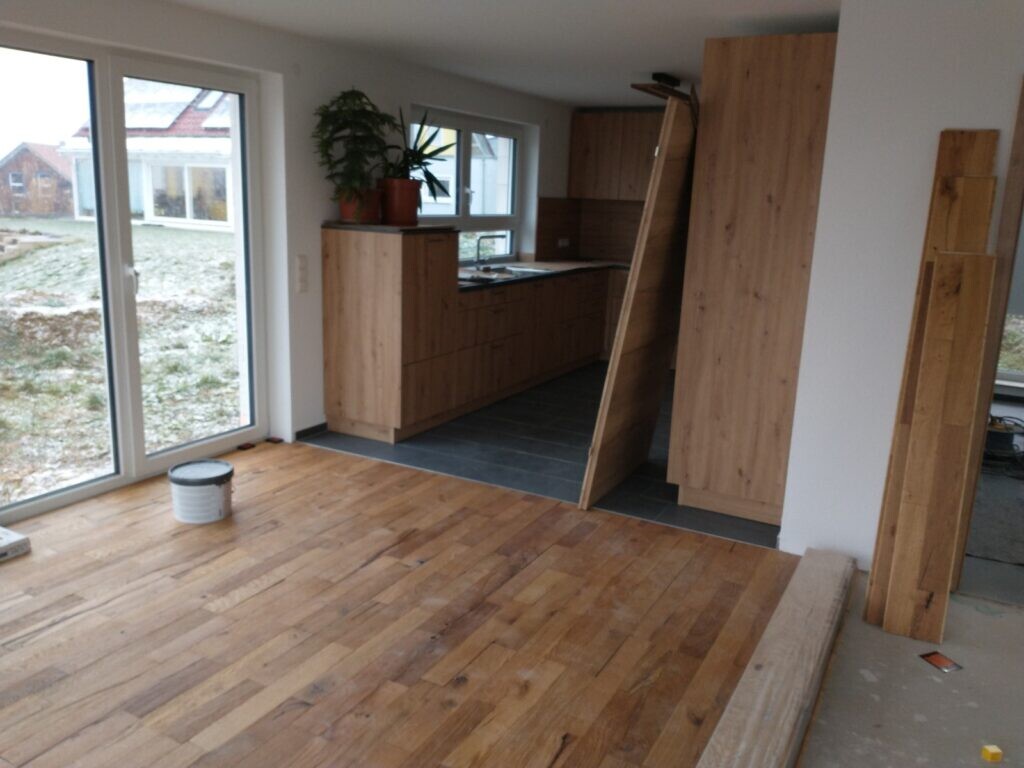 Offener Wohnraum mit Holzboden, holzfarbene Küchenfronten und Bauarbeiten im Innenbereich