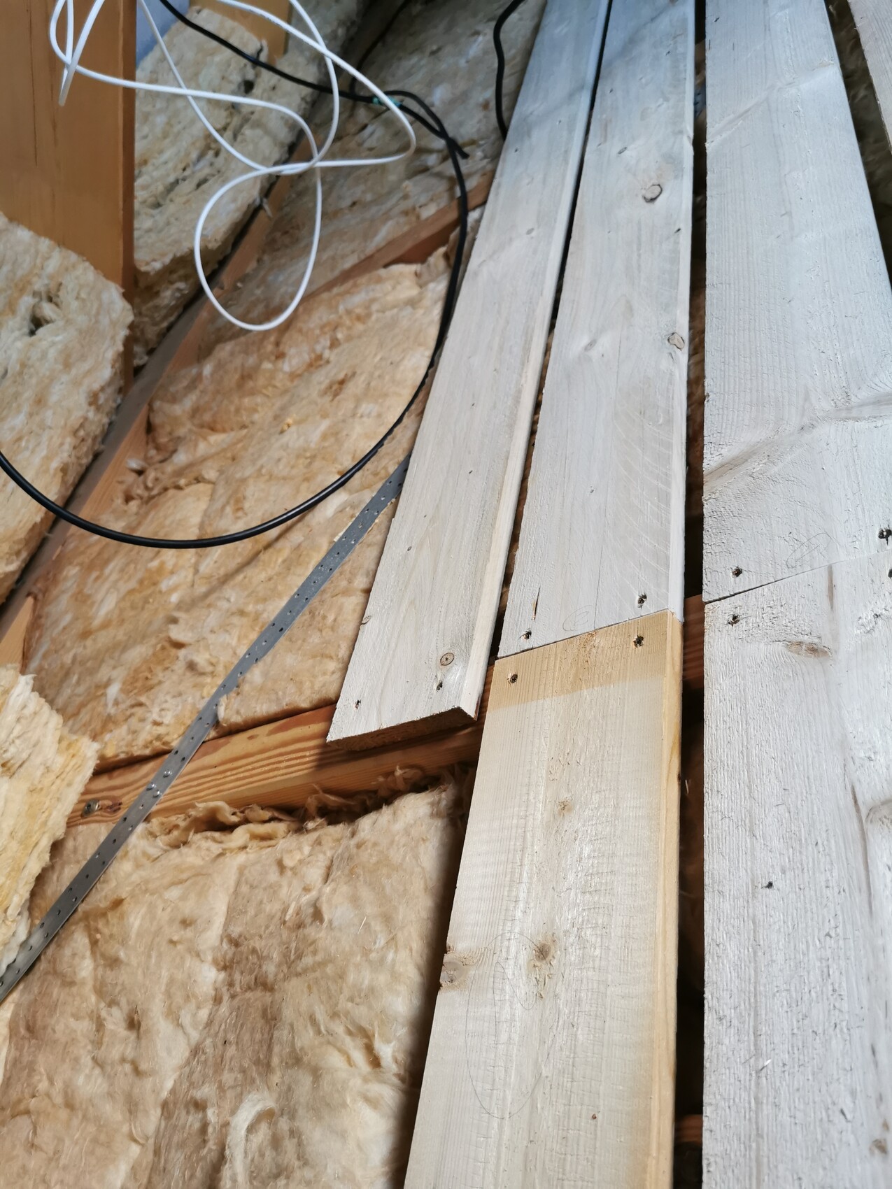 Rohbau-Szene: Holzplanken, lose Dämmung und Kabelsalat zwischen Wänden.