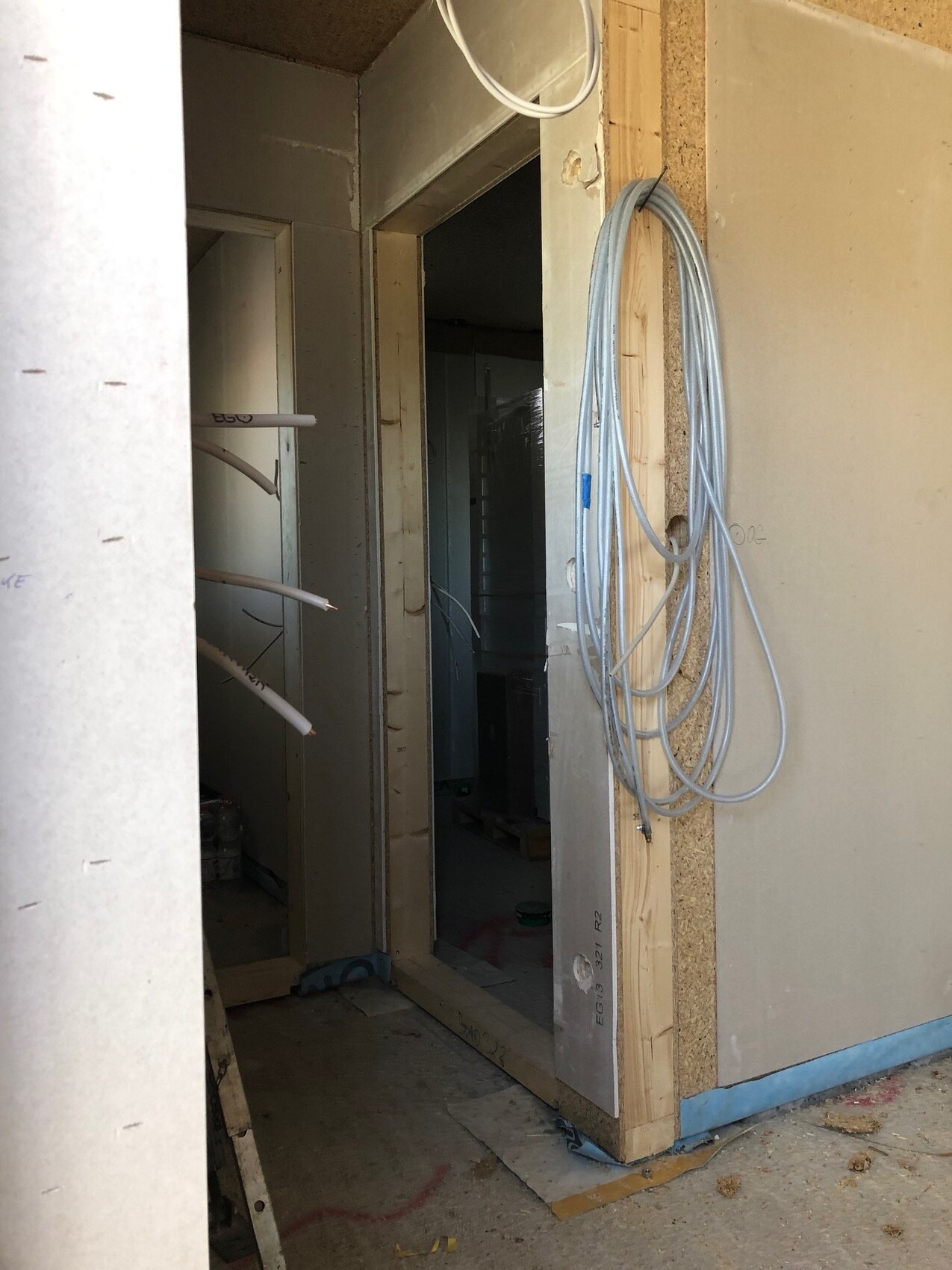 Baustelle: Innenraum mit Holzrahmen, lose Kabelschlaufen hängen an der Wand.