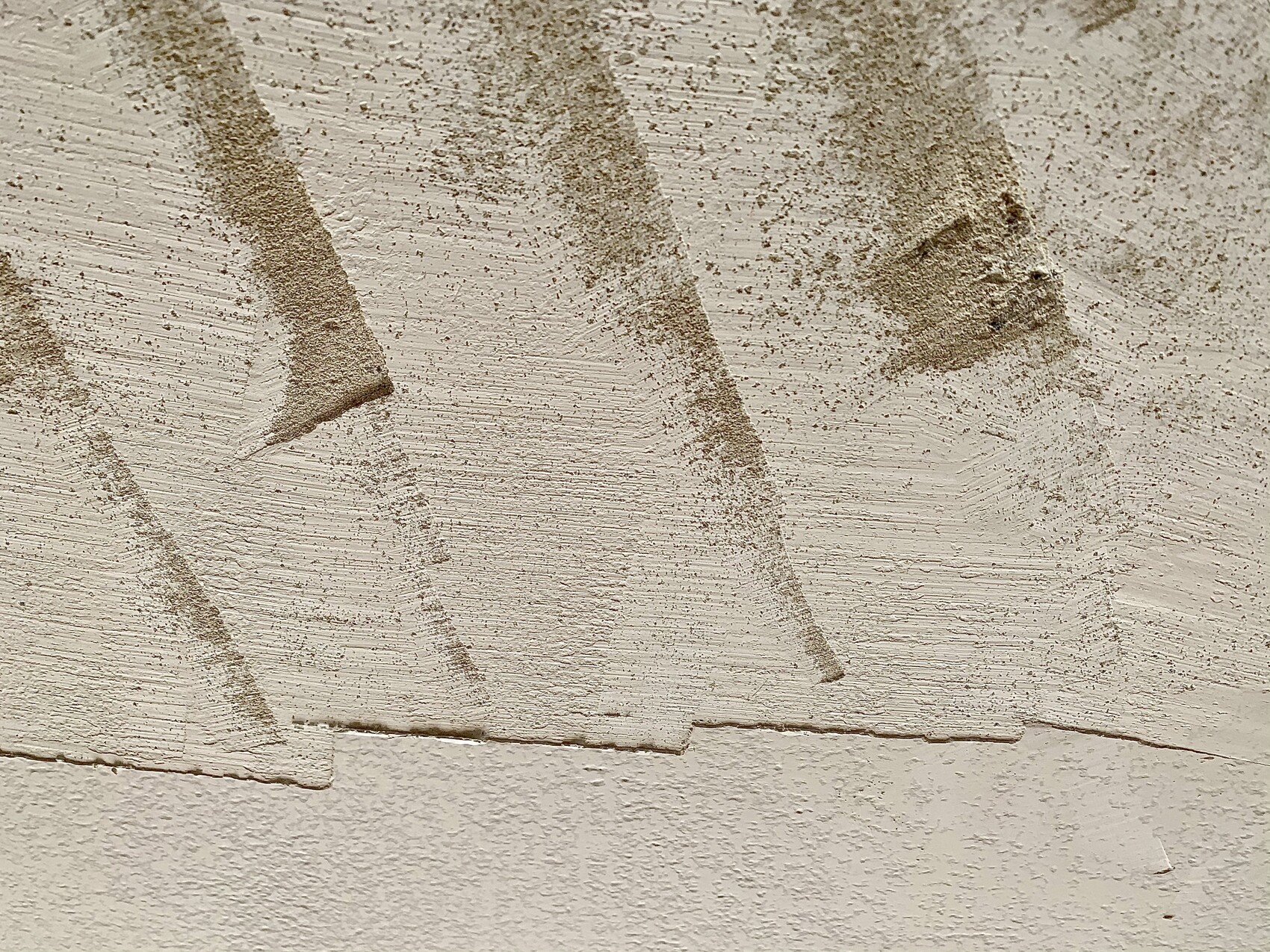 Nahaufnahme einer verputzten Wand mit rauer Struktur und Staubkörnern