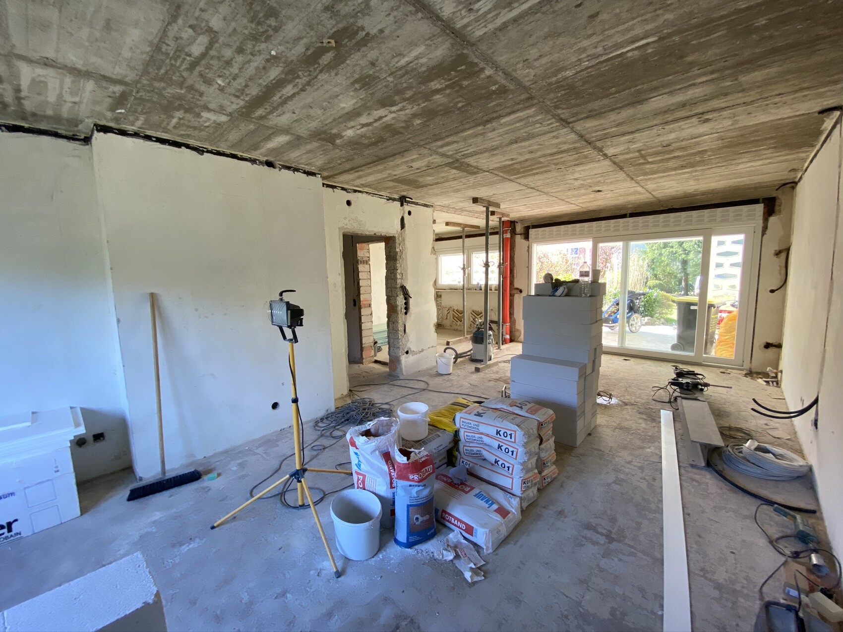 Innenraum einer Baustelle: Rohbau, Bauleuchten, Styroporblöcke, Bauszubehör, Glas-Schiebetür.