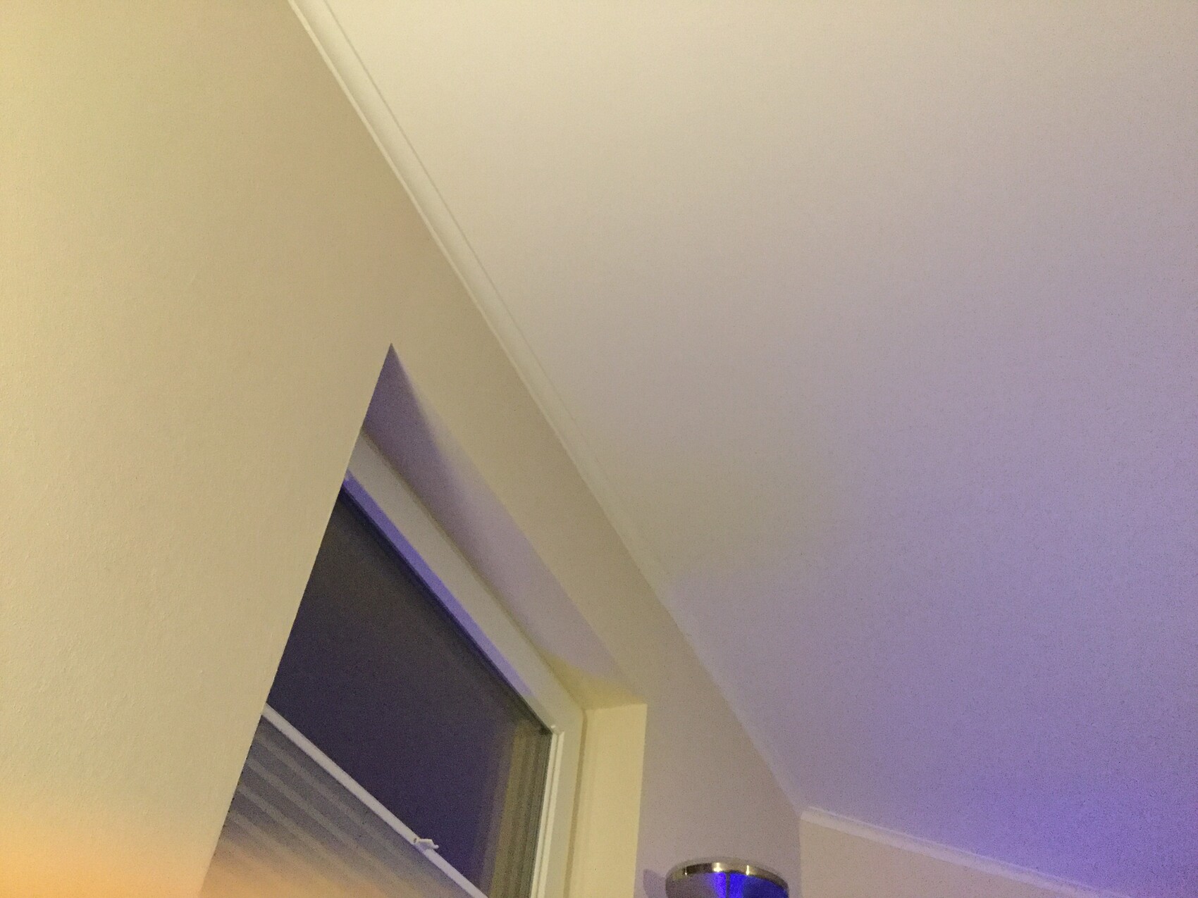 Innenraumecke mit Fenster und blau-lila Beleuchtung an Decke und Wand