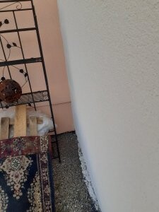 Innenraum-Ecke mit Metallregal, Teppich und kleinem Möbelstück
