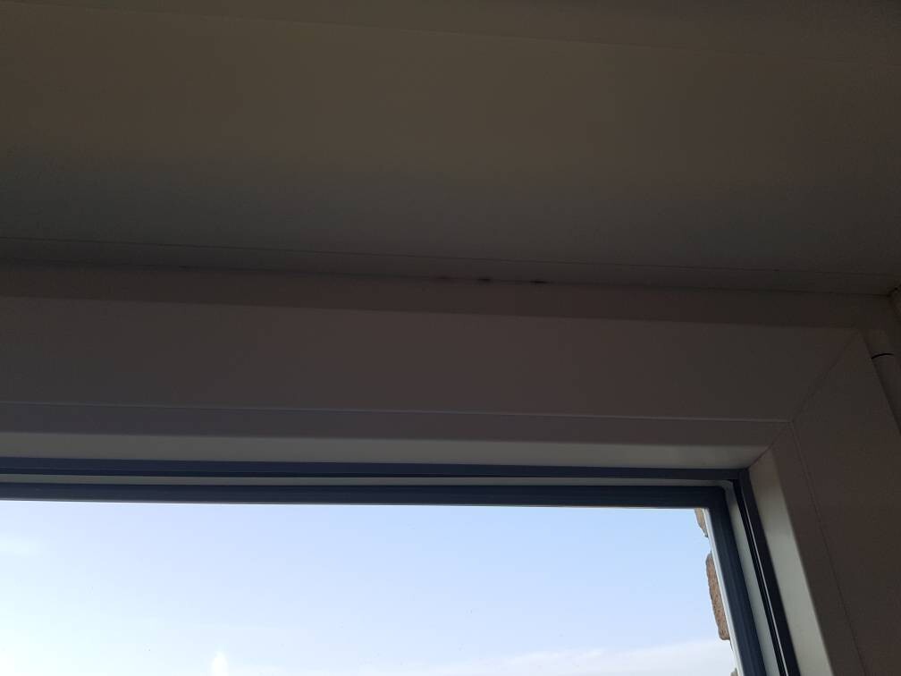 Blick durch Fenster im Innenraum auf blauen Himmel, weiße Innenwände und Fensterrahmen.