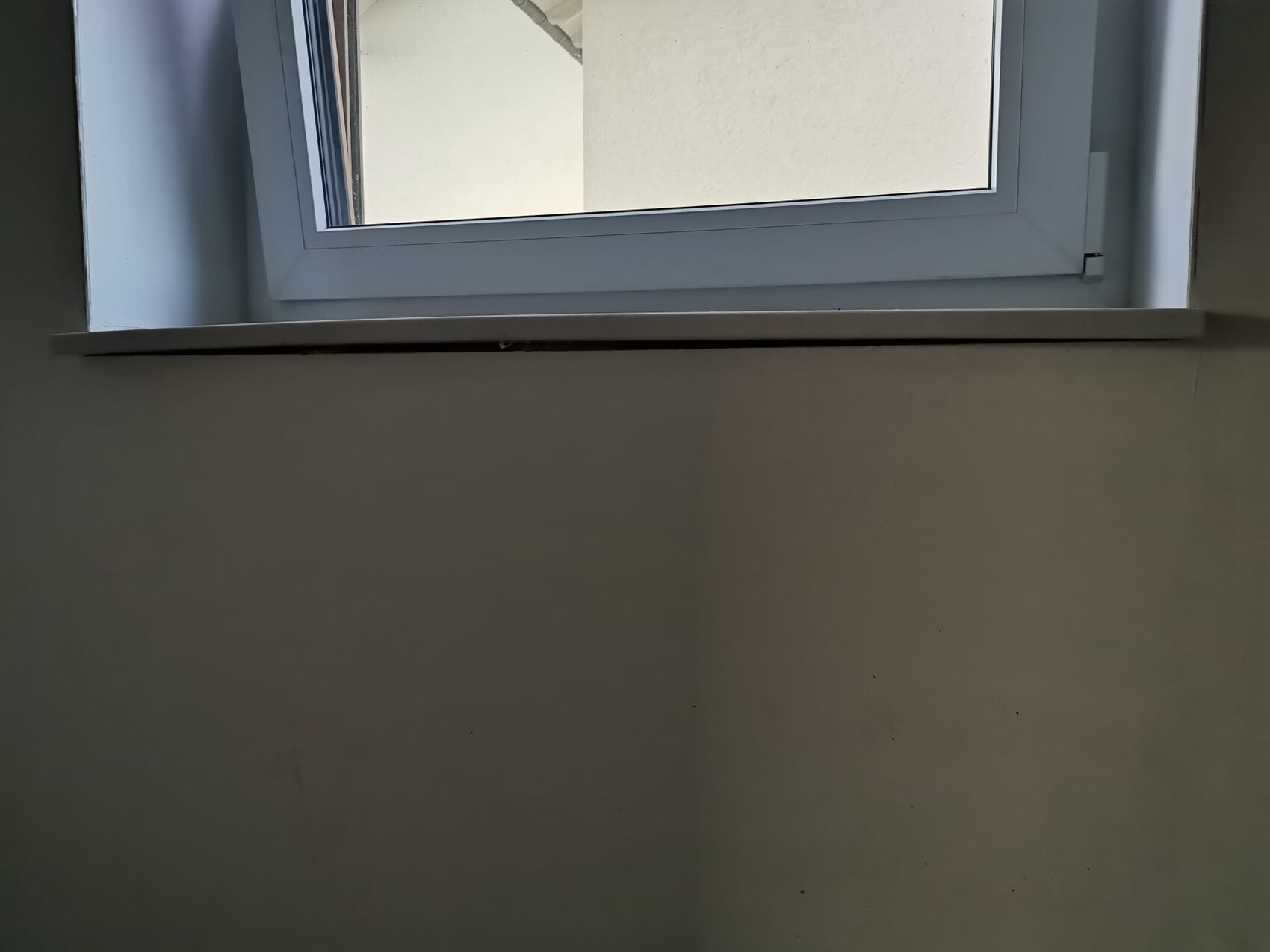 Weißer Fensterrahmen mit Fensterbank an einer hellen Wand, Innenaufnahme eines Fensters.