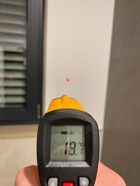 Infrarot-Thermometer mit orange Oberseite, Display zeigt 19,0 °C, Laserpunkt an Wand