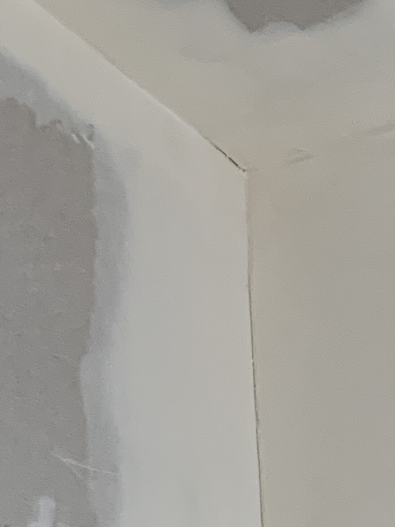 Weiß gestrichene Innenwand und Decke mit deutlich sichtbarem Riss an der Ecke.