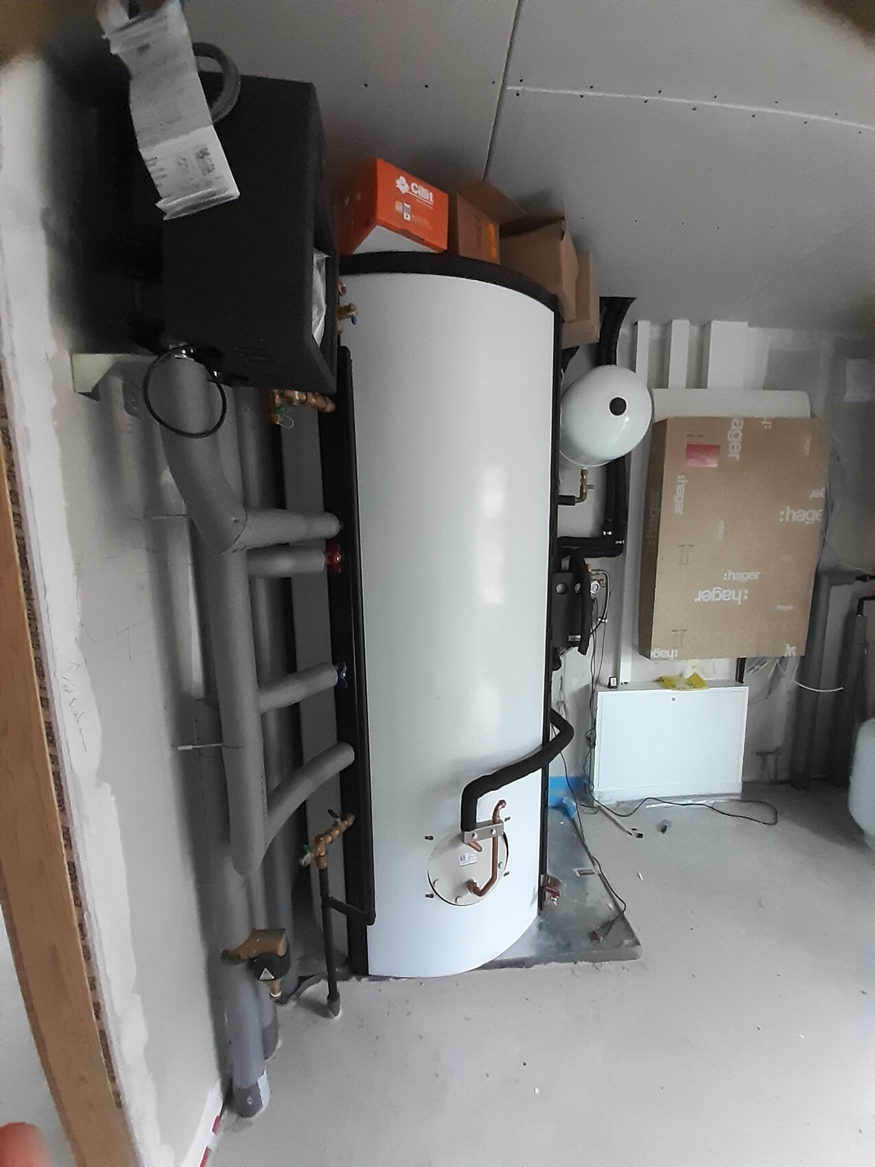 Warmwasserspeicher im Keller mit Rohren, Anschlüssen und Kartonboxen.