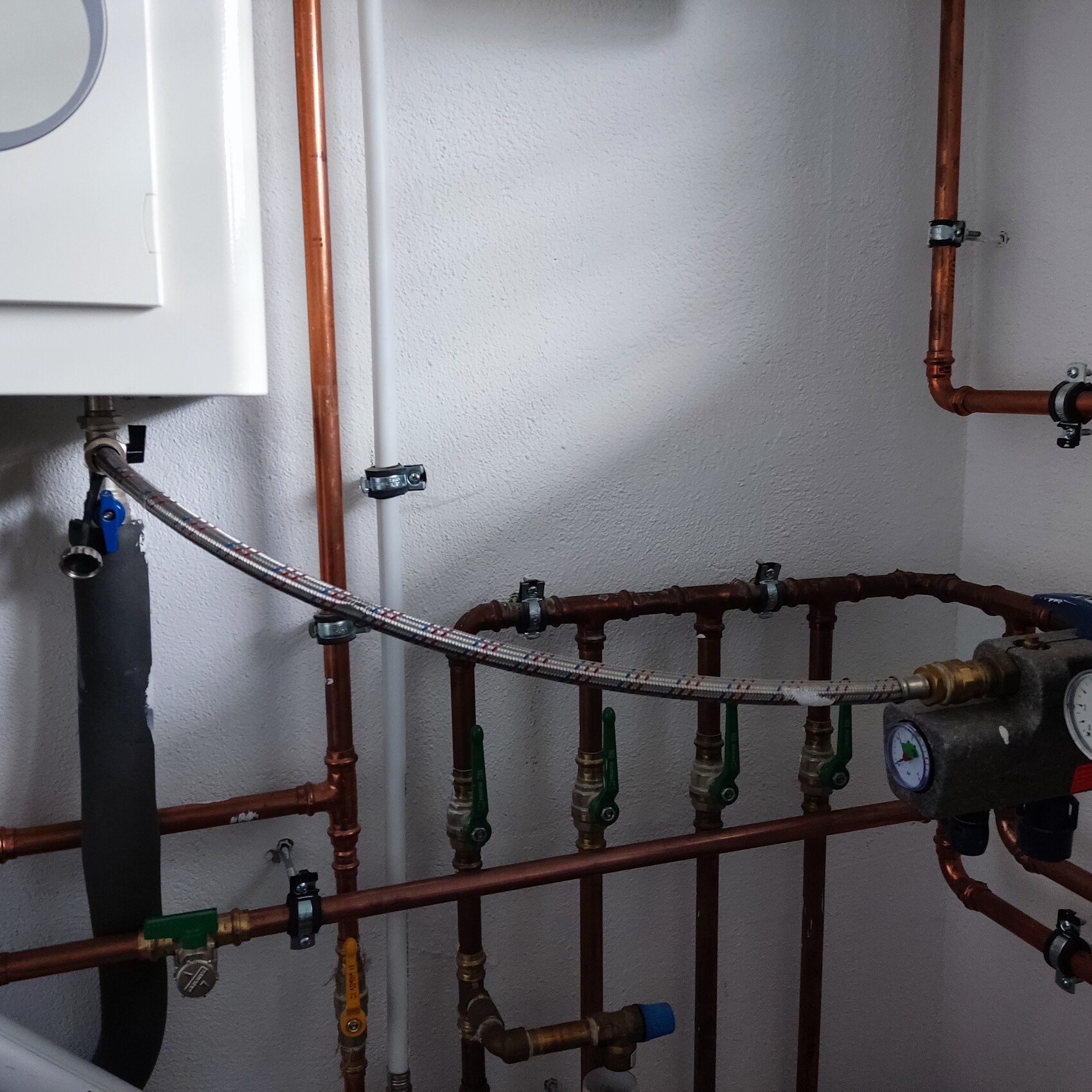 Heizungsanlage mit Kupferrohren, Ventilen und Druckanzeige im Technikraum.