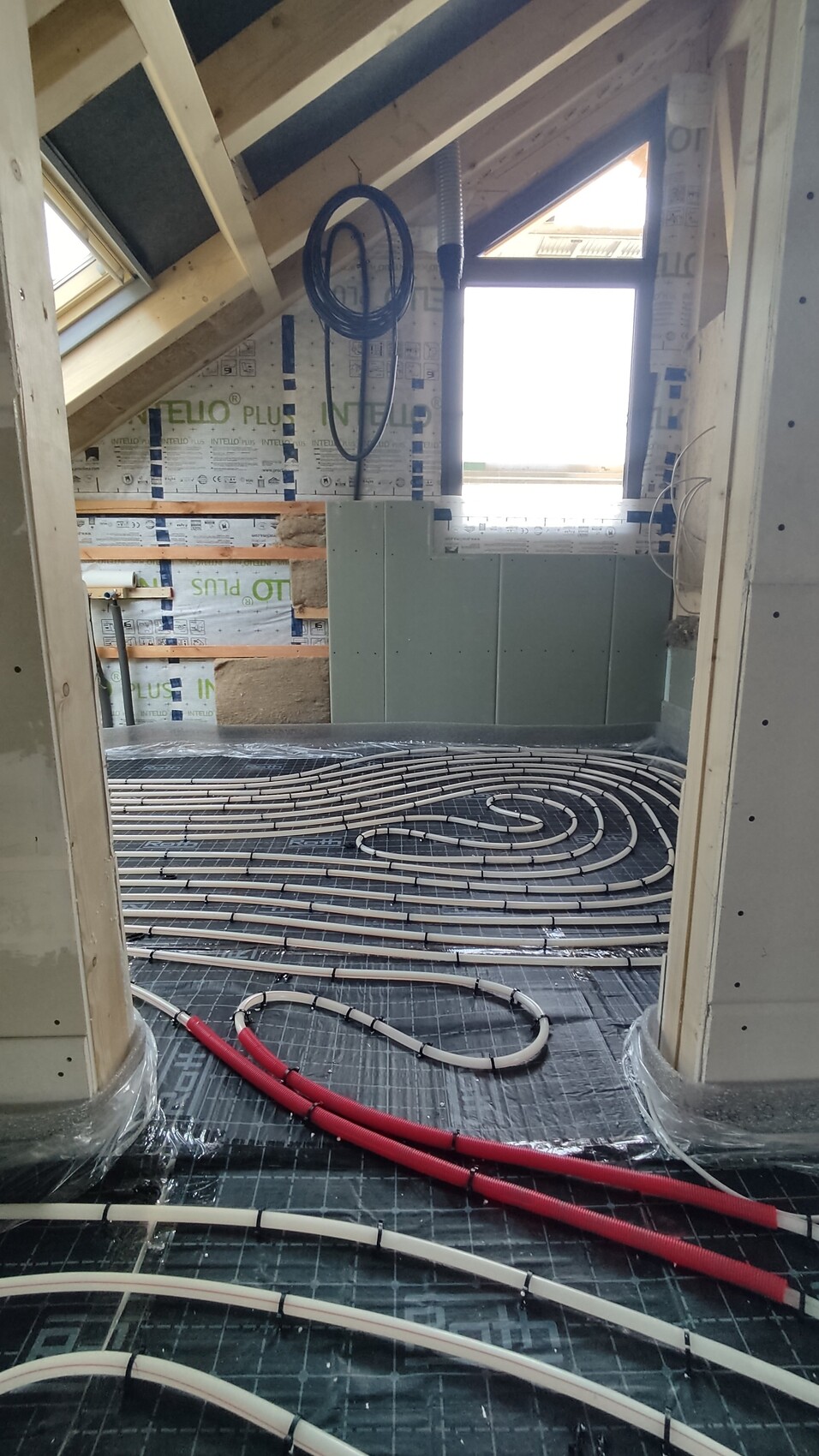 Dachgeschoss im Bau: Fußbodenheizungsschlangen, Dämmplatten, Fenster und Installationen.