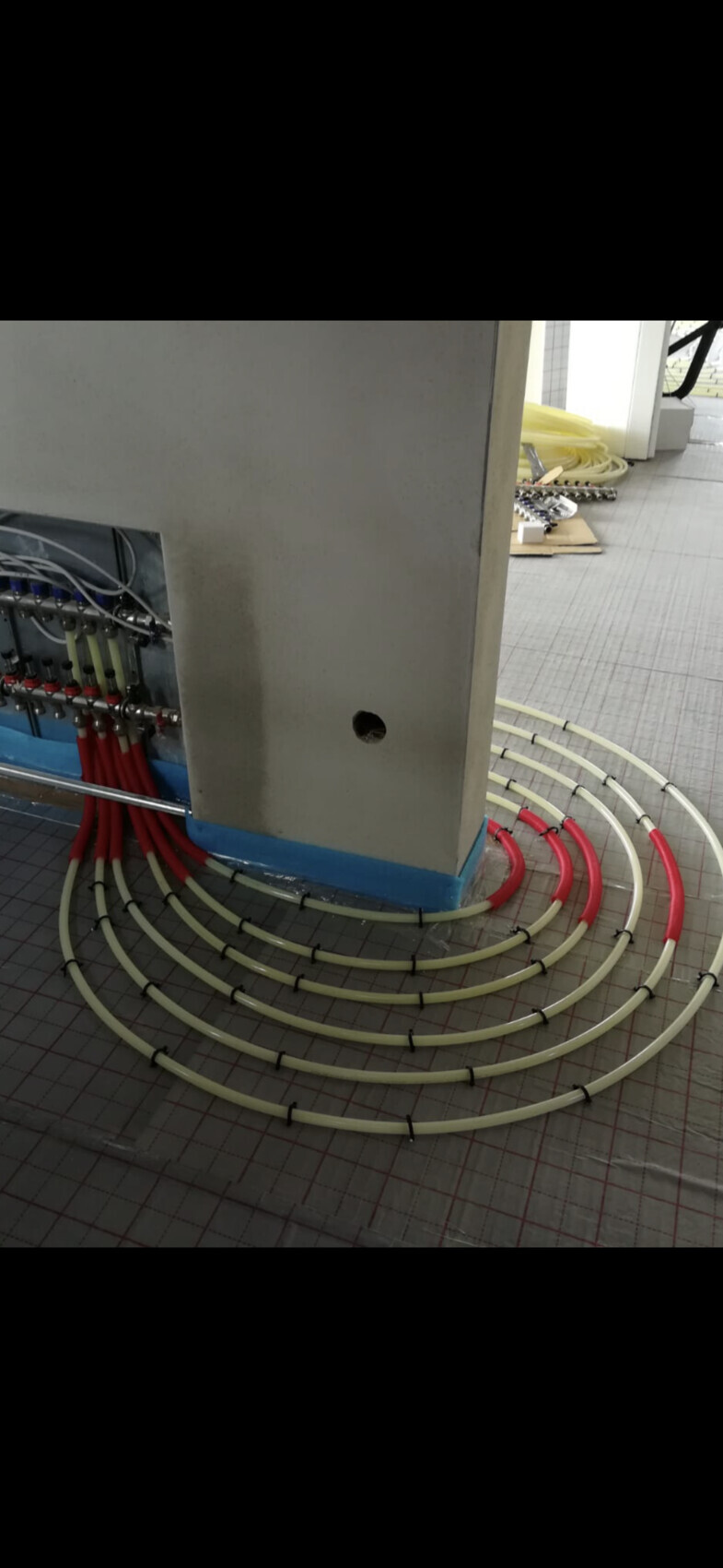 Kabelbündel und Rohre in rot/weiß spiralförmig um eine Säule einer technischen Anlage.