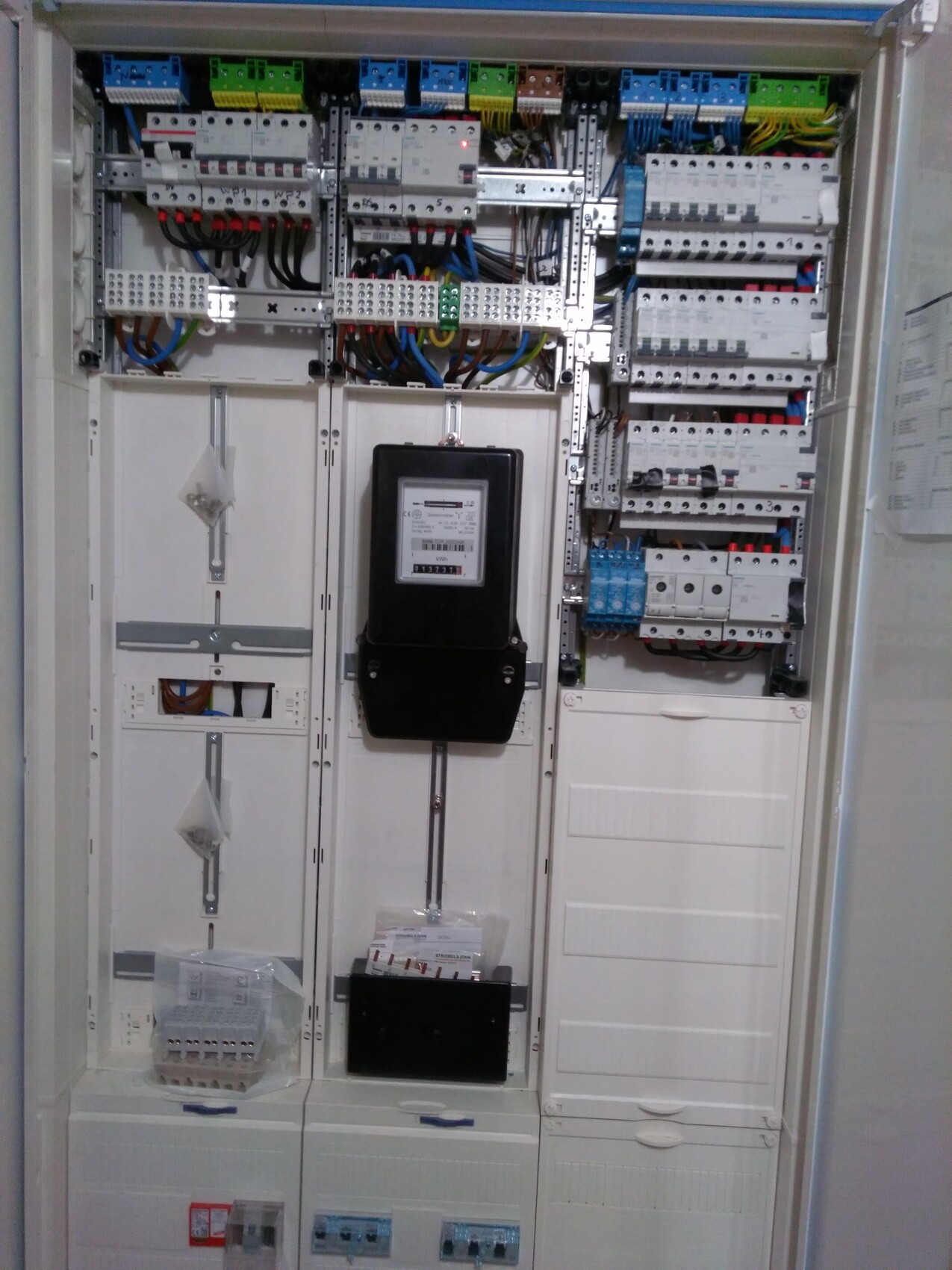 Schaltschrank mit Zähler, Sicherungen und vielen Kabeln der Elektroinstallation.