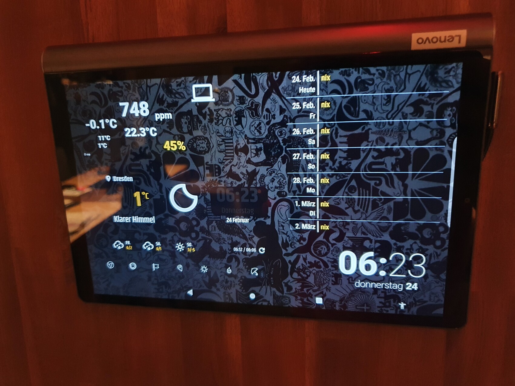 Tablet mit dekorativem Hintergrund zeigt Wetter, Uhrzeit und Termine auf Holzwand