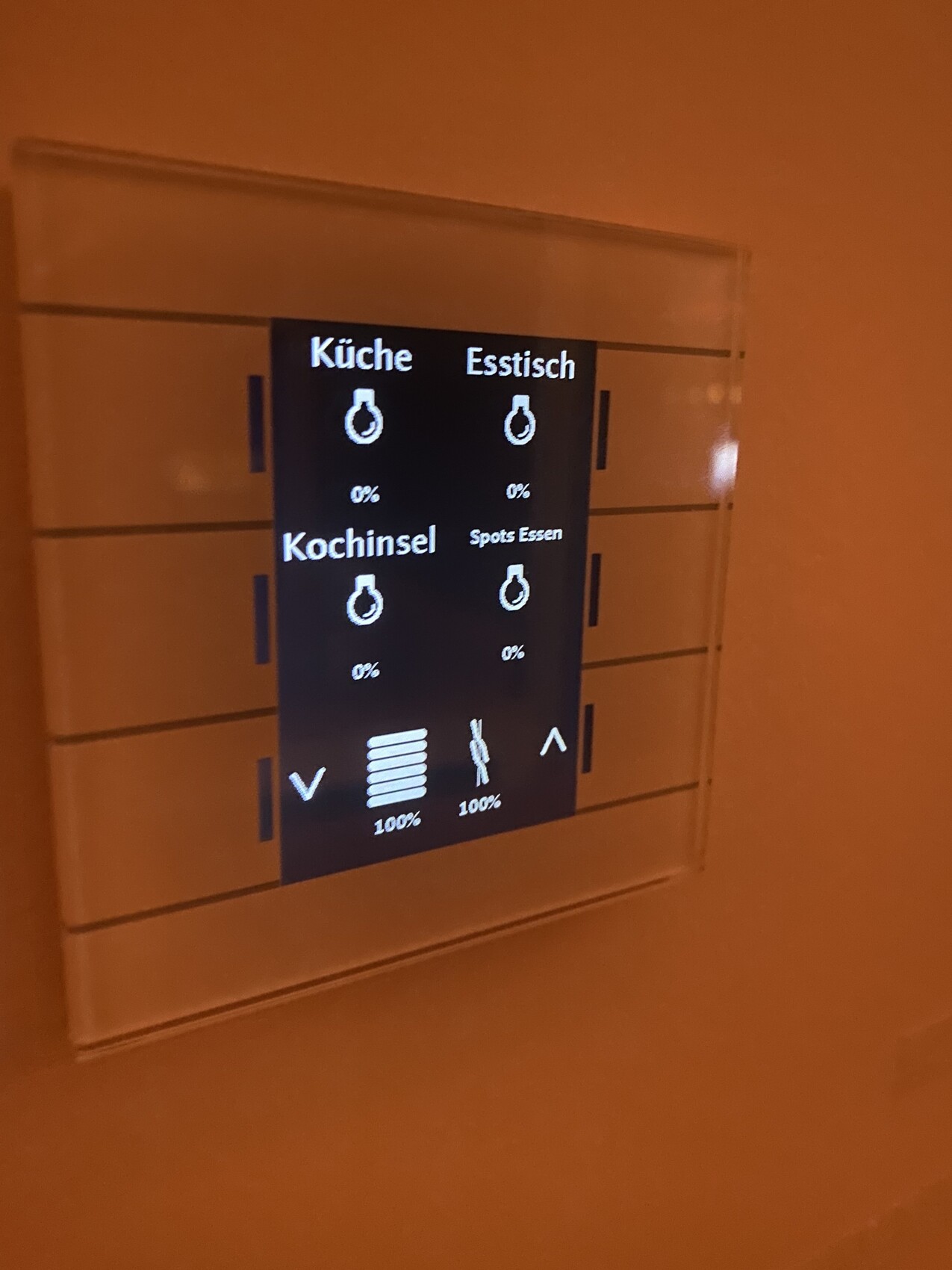 Smart-Home-Touchscreen in einer Wandnische, zeigt Küche, Esstisch, Kochinsel und Spots.