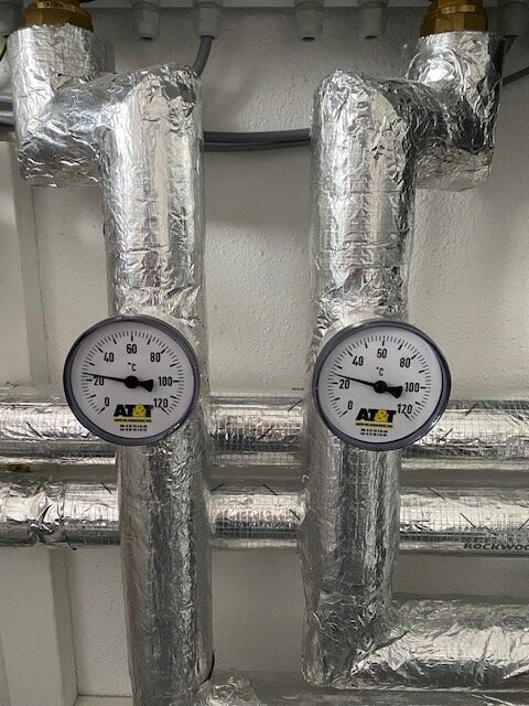 Zwei isolierte Heizungsrohre mit Messgeräten in einer Haustechnik-Installation