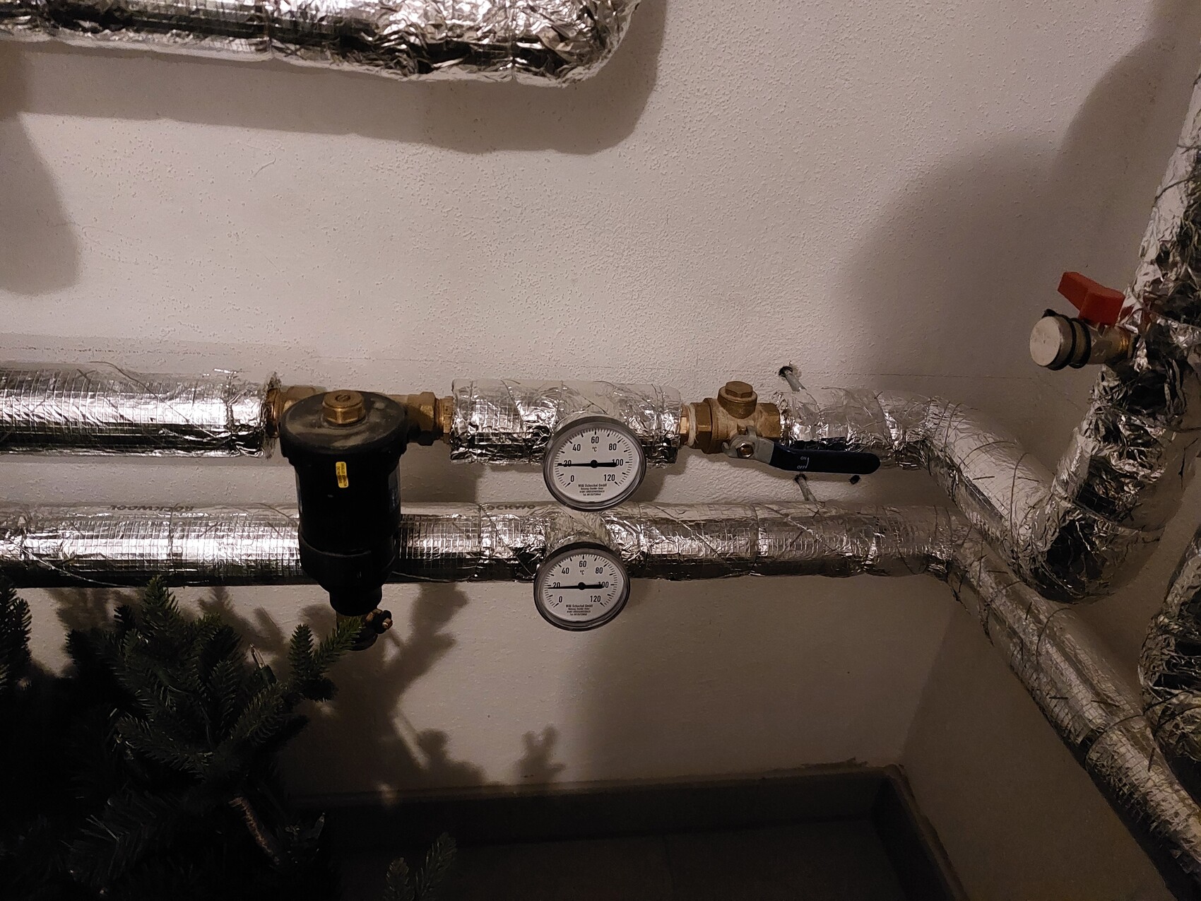 Isolierte Rohre mit zwei Druckmessern und Ventil im Heizungskeller