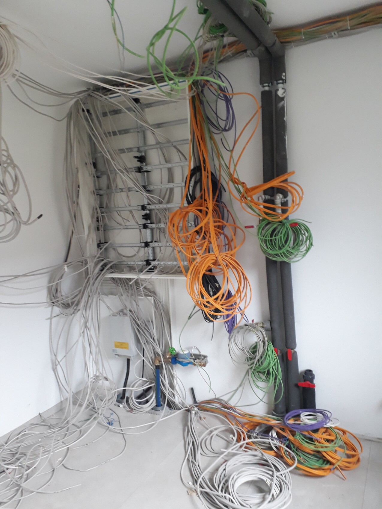 Chaotischer Kabelsalat um Patchpanel mit bunten Netzwerkkabeln.
