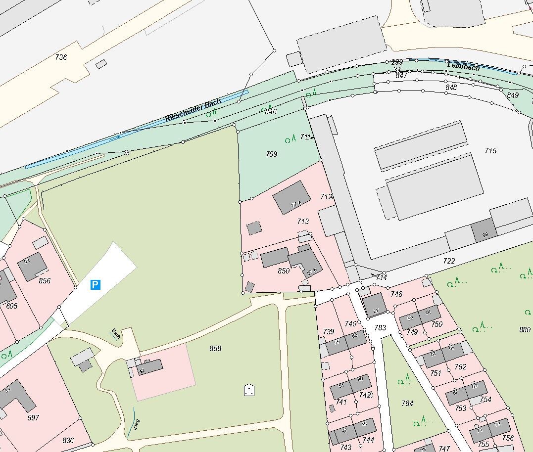 Kartenabschnitt einer Stadt mit Bach, Straßen, Gebäuden, Parkplätzen und Grünflächen.