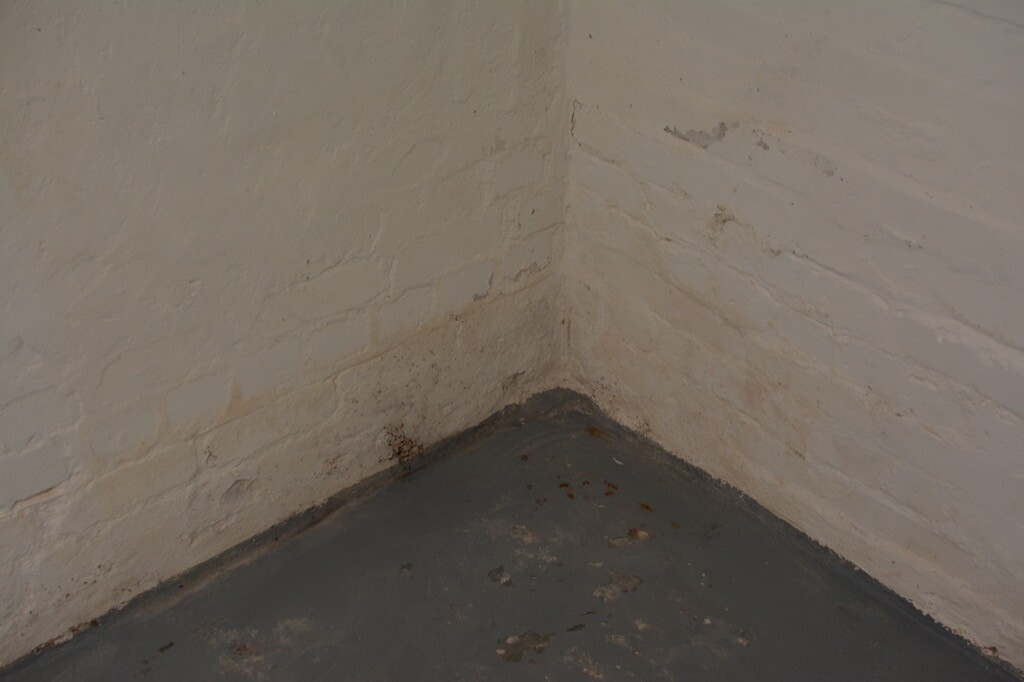 Keller-Ecke mit feuchter Wand und feuchtem Boden, Feuchtigkeitsspur