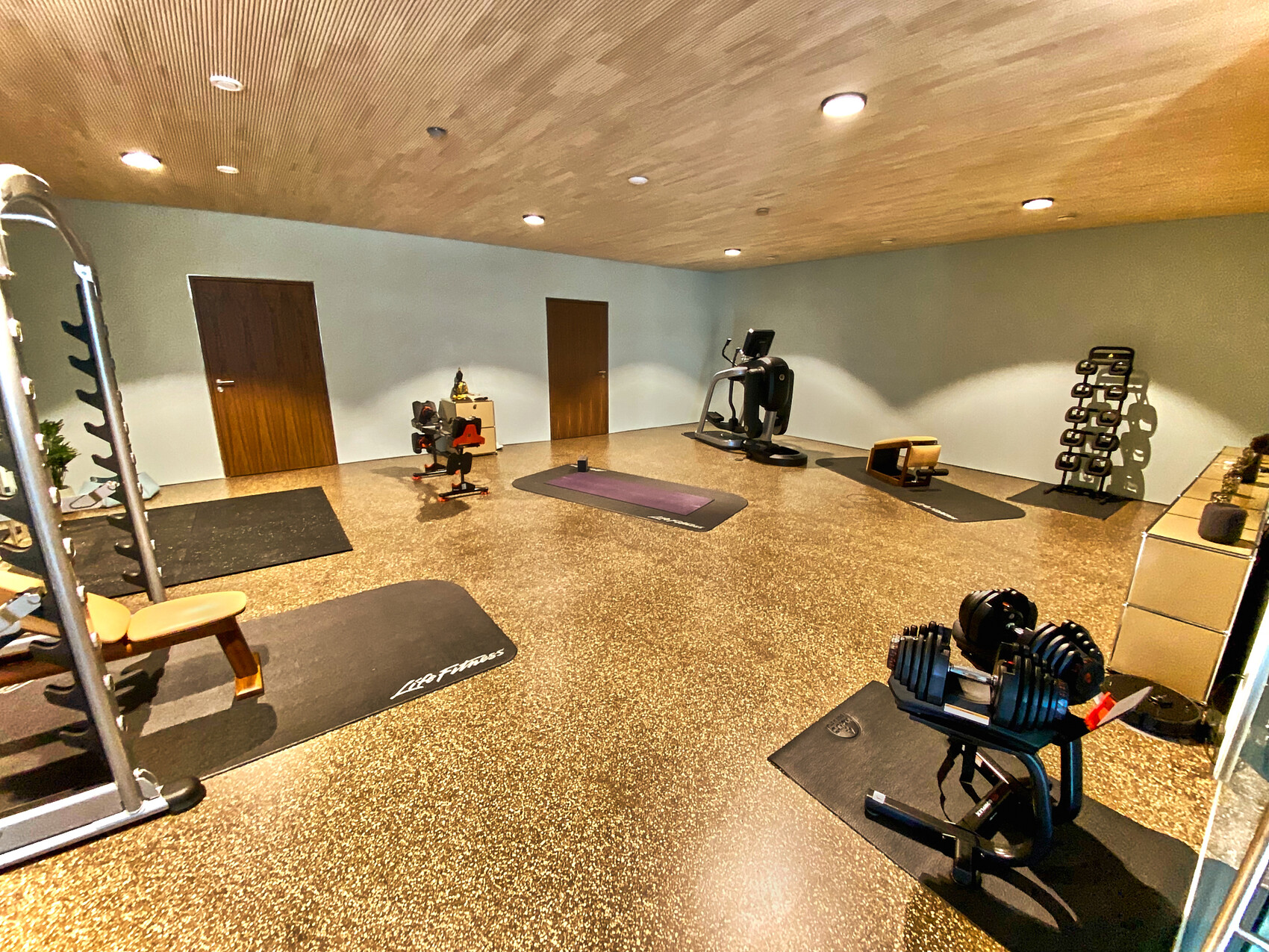 Privater Fitnessraum mit Hantelbank, Matte, Hanteln, Gewichte, Laufband und Hantelständer