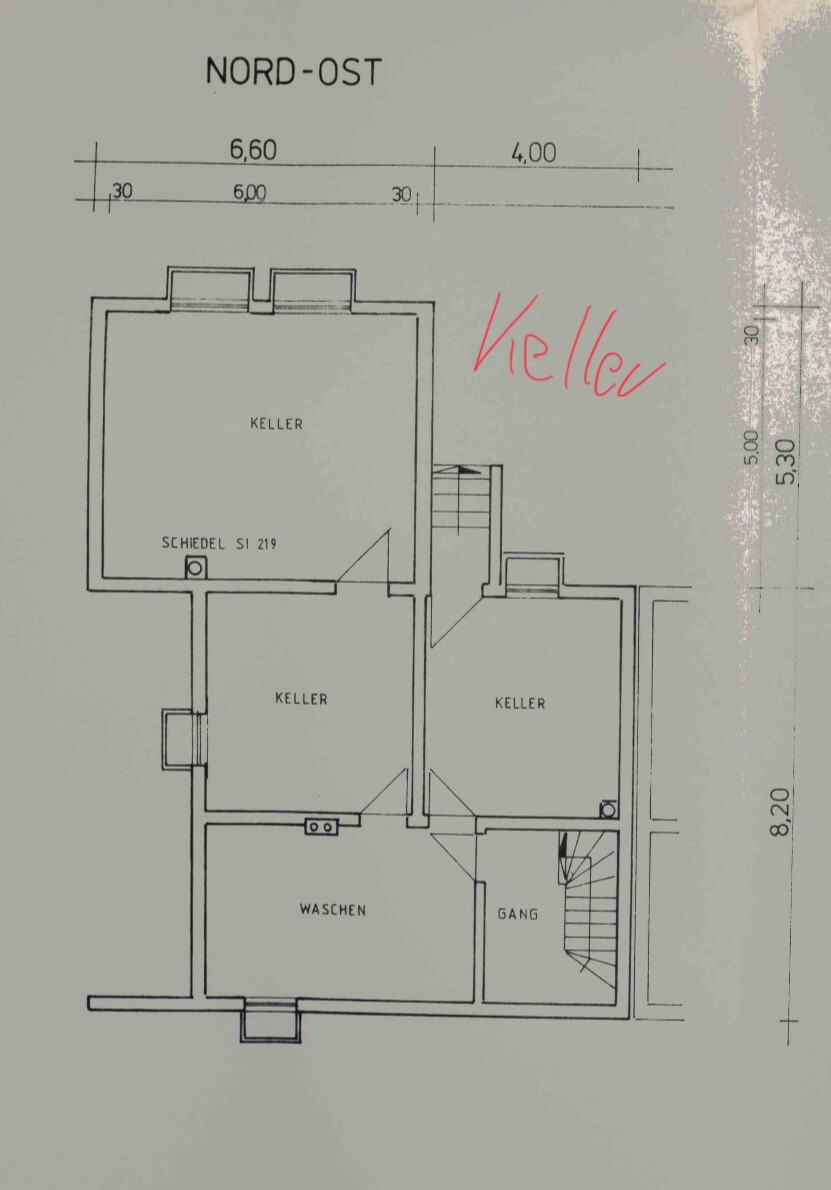 Grundriss Kellergeschoss: drei Kellerraeume, Waschen, Gang und Treppe; Nordost-Ausrichtung.