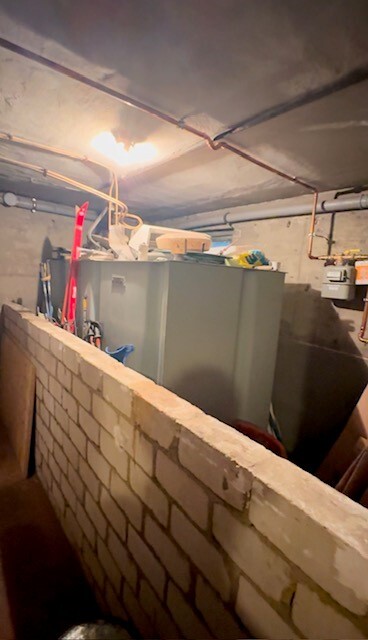 Keller-Heizungsraum mit Heizkessel, Rohren, Ziegelwand und Werkzeugen.