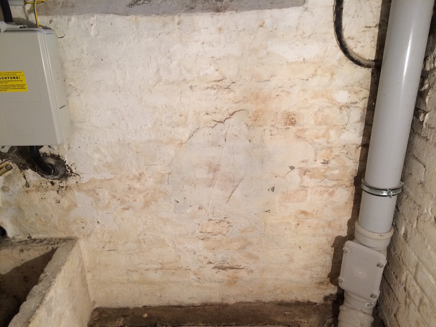 Kellerwand mit Haustechnikrohren, Abflussrohr und Befestigungen