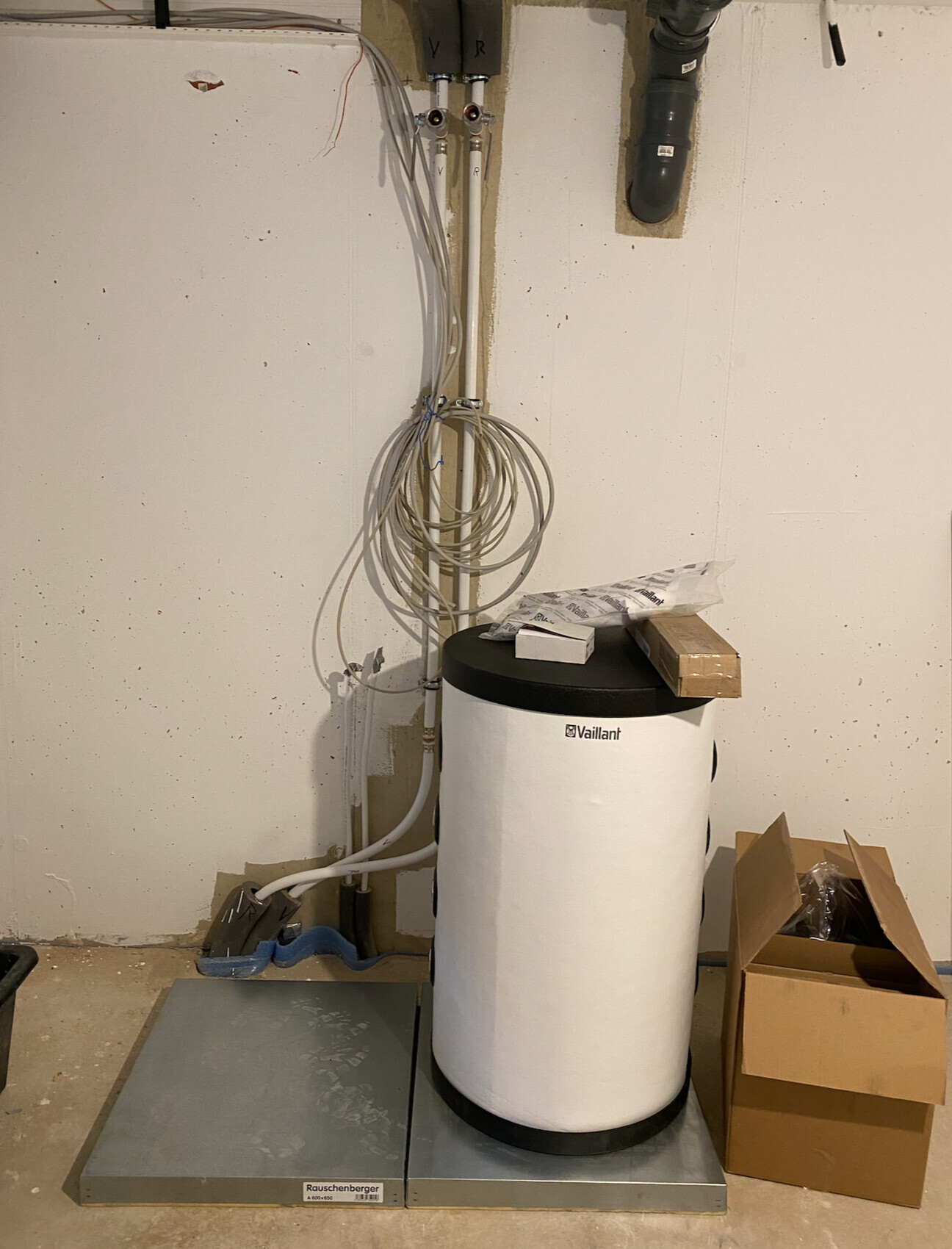 Vaillant-Warmwasserboiler im Keller; lose Kabelstränge an der Wand, Karton daneben.