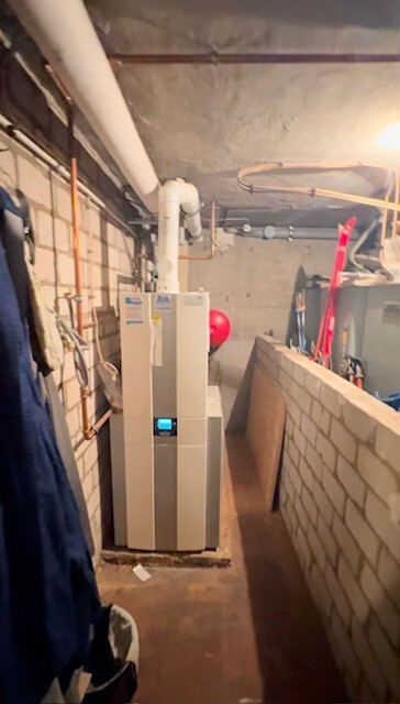 Keller mit Heizkessel, Rohrleitungen an der Decke, Bruchsteinwand rechts, schmaler Gang.