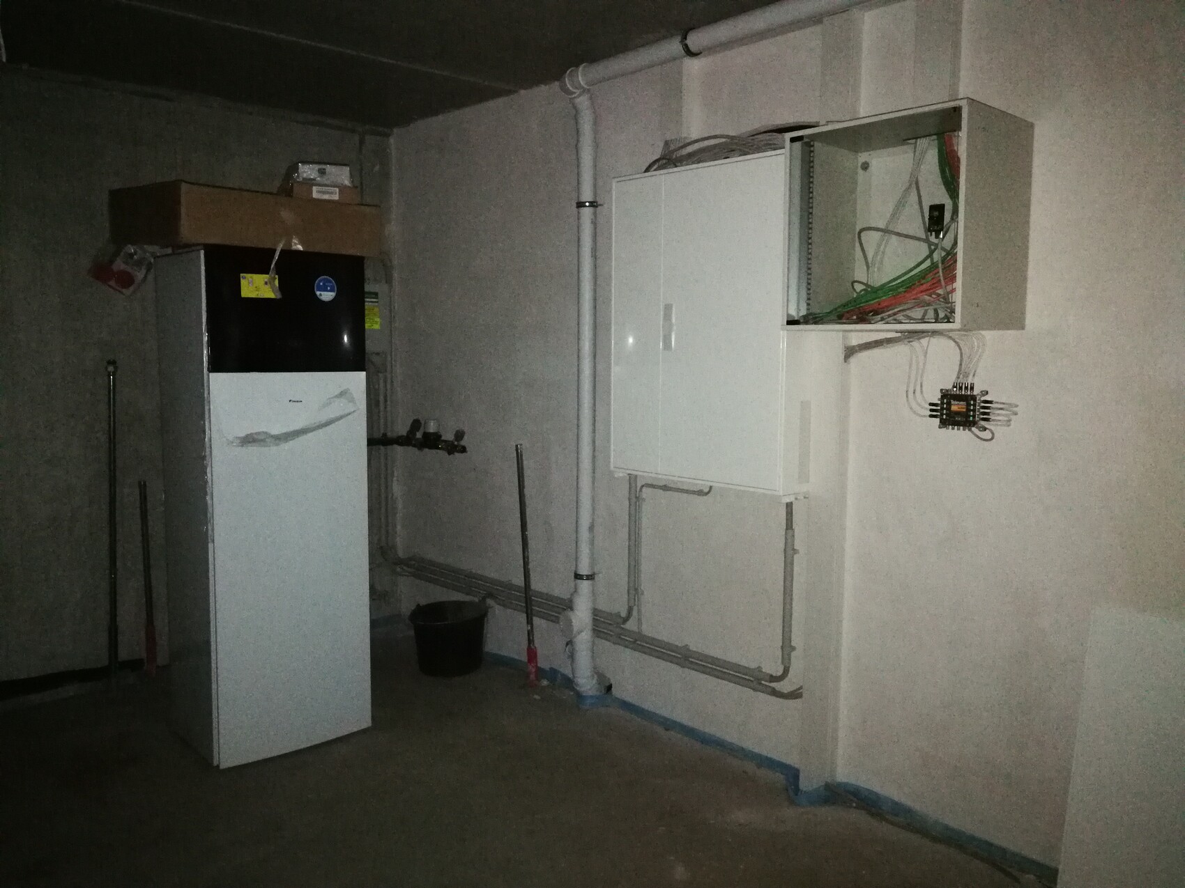 Kellerraum mit Heizkessel links, offenem Elektro-Schaltschrank und Kabelbündeln rechts.