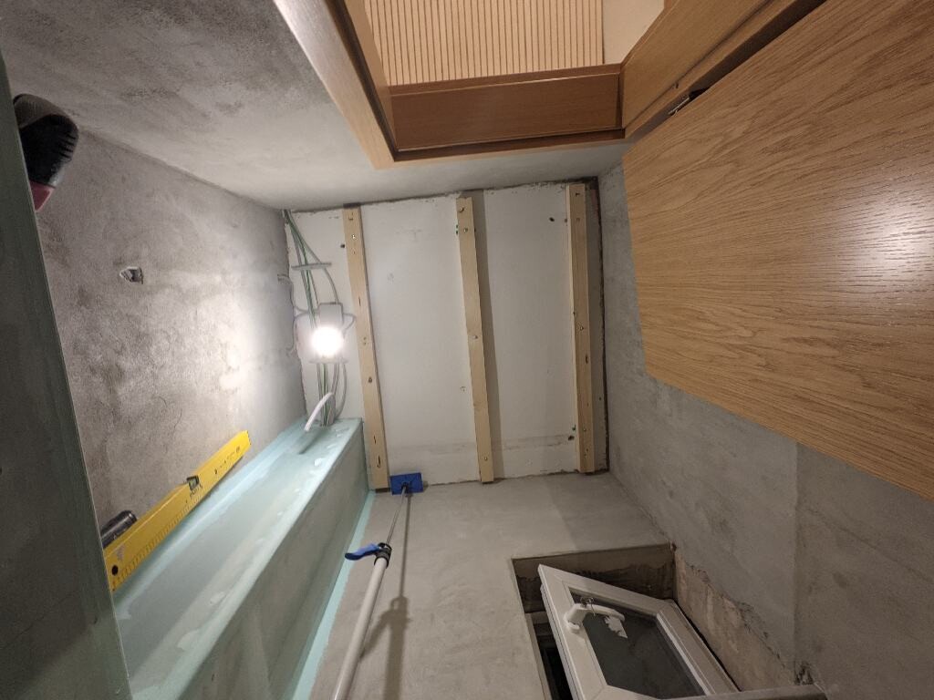 Keller-Rohbau mit Holzlatten, Fenstern, Kabeln und Bauwerkzeugen.