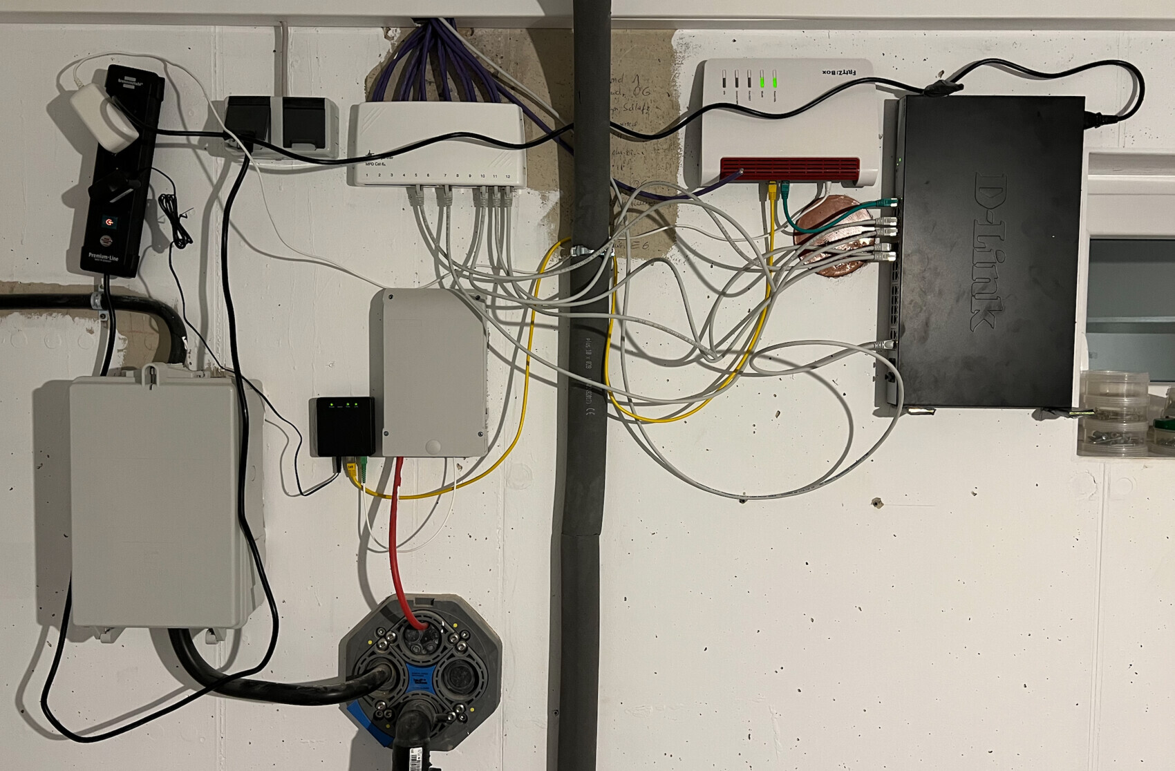 Wandmontiertes Netzwerksystem mit Router und Switch sowie vielen Ethernet-Kabeln an der Wand.
