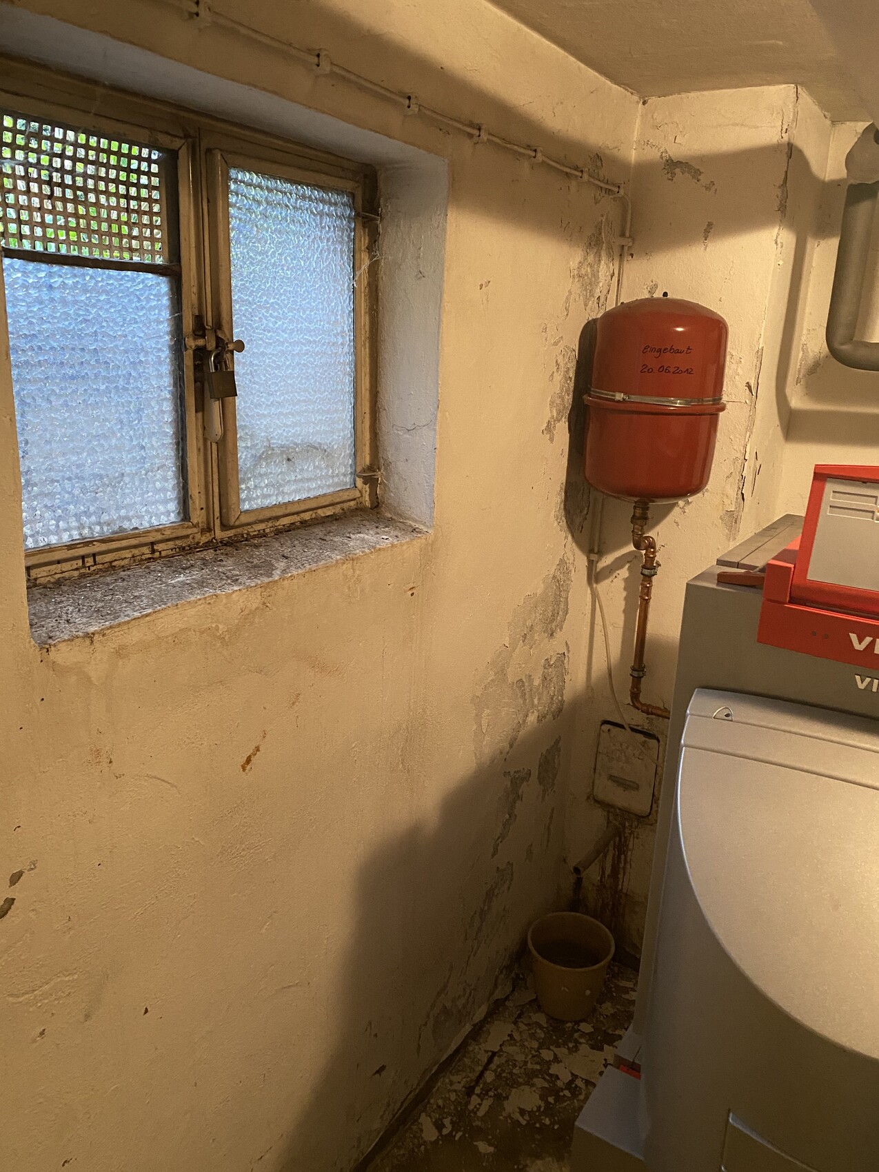 Keller-Wäschebereich: Waschmaschine rechts, rotes Ausdehnungsgefäß an Wand, kleines Fenster.