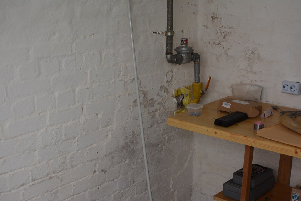 Kellerbereich mit sichtbaren Rohrleitungen, Ventil und Werkbank mit Werkzeugen