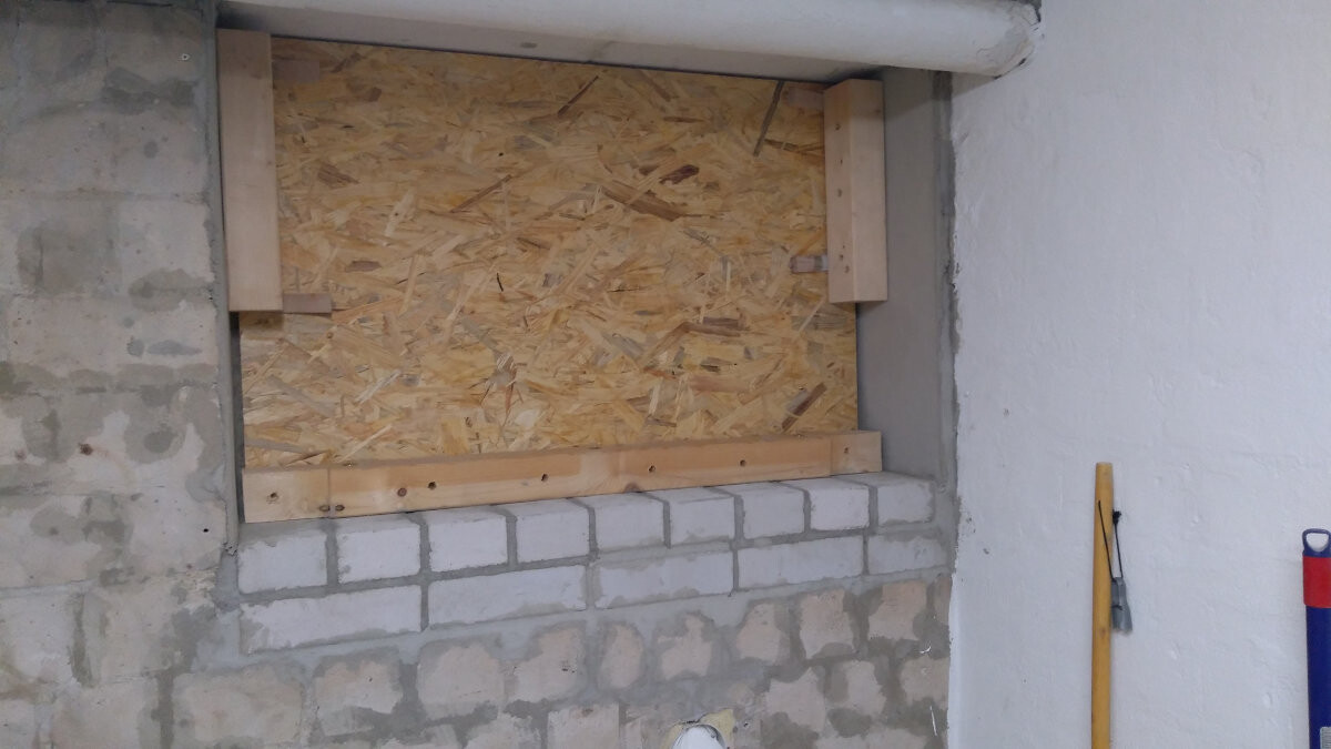 Kellerfenster durch OSB-Platte verschlossen, Rahmen aus Holz, Mauerwerk sichtbar