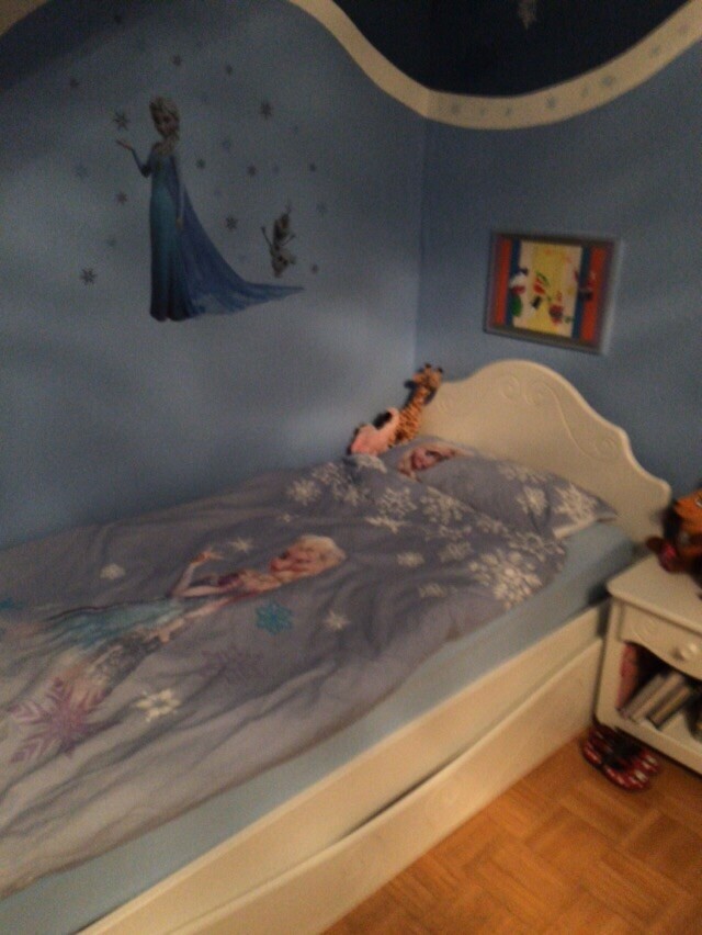 Kleines Kinderzimmer mit Elsa-Wanddeko, hellblaue Bettwäsche, weißem Bettgestell und Nachttisch.