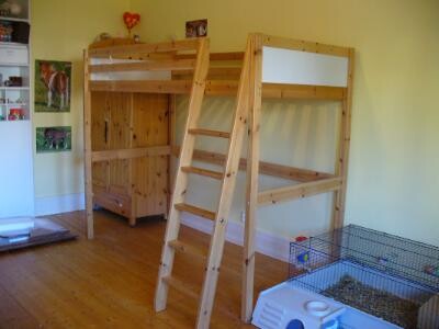 Kinderzimmer mit zwei Hochbetten aus Holz, Holzboden und Käfig rechts.