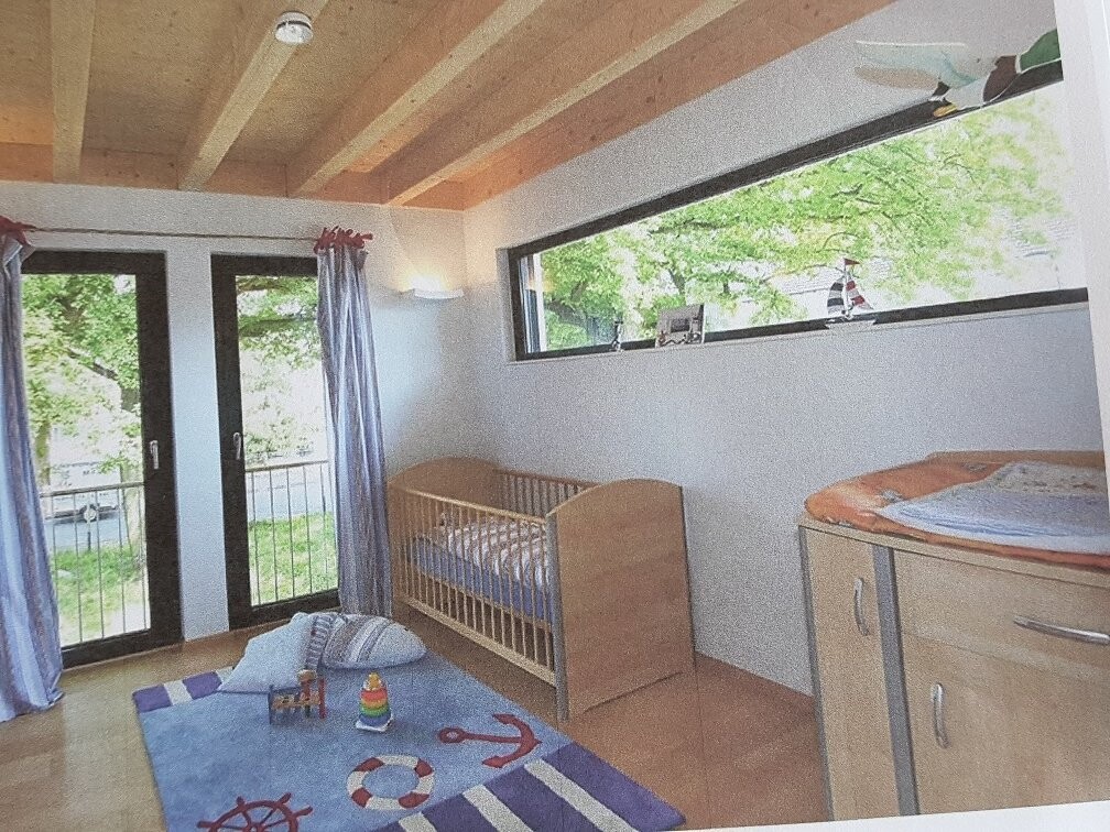 Kinderzimmer mit Krippe, Kommode, Spielmatte, Balkontür und Fensterfront