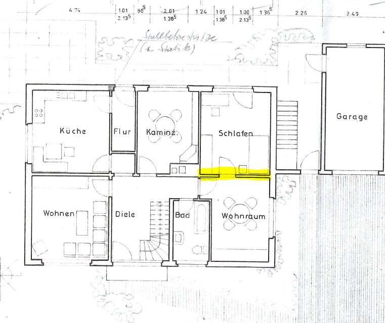 Grundriss eines Hauses mit Küche, Flur, Kamin, Schlafen, Bad, Wohnraum, Garage; gelb markierte Wand