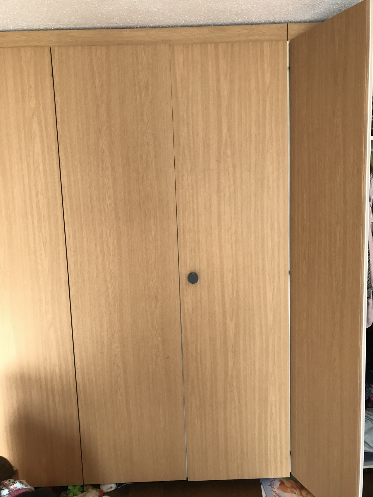Großer Holzschrank mit glatten Türblättern und rundem dunklen Griff im Schlafzimmer