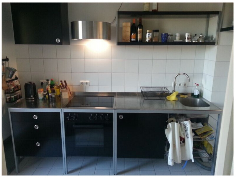 Kompakte Küche mit Cerankochfeld, Backofen, Spüle, Geschirrkorb und schwarzen Unterschränken.