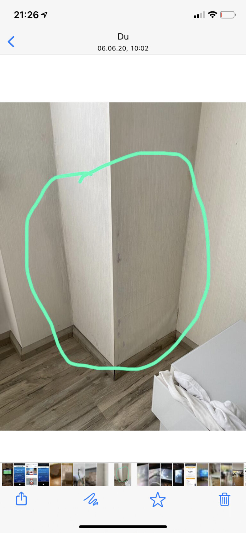 Grün markierte Ecke eines Holzschranks mit senkrechter Fuge und Bodenleiste.