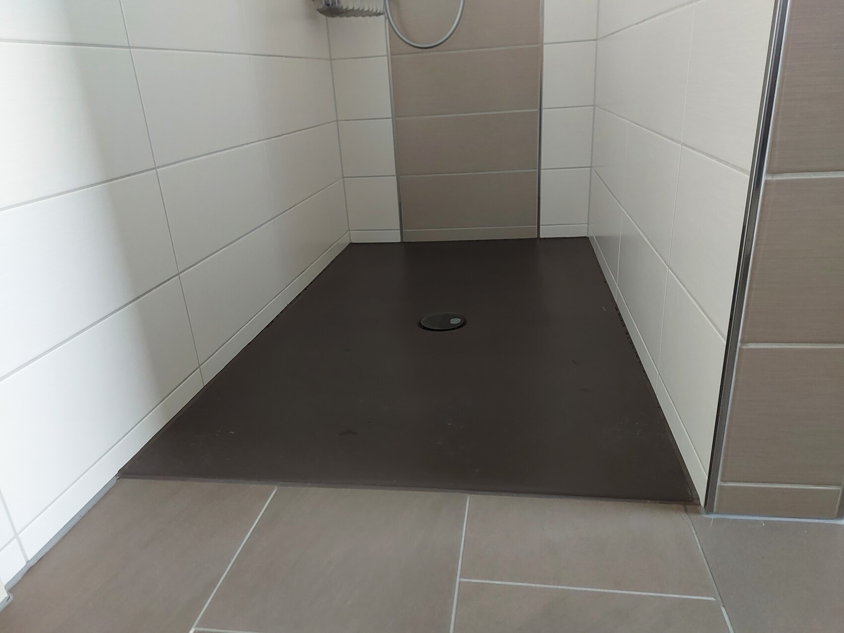 Kleines Badezimmer mit Dusche, weißen Wandfliesen und dunkler Duschwanne