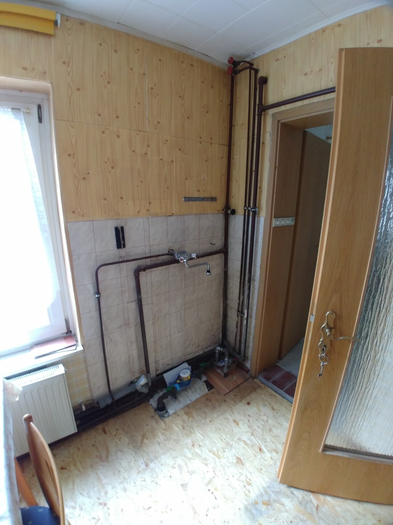 Kleines Badezimmer mit offenen Rohren und Holzverkleidung während Renovierung