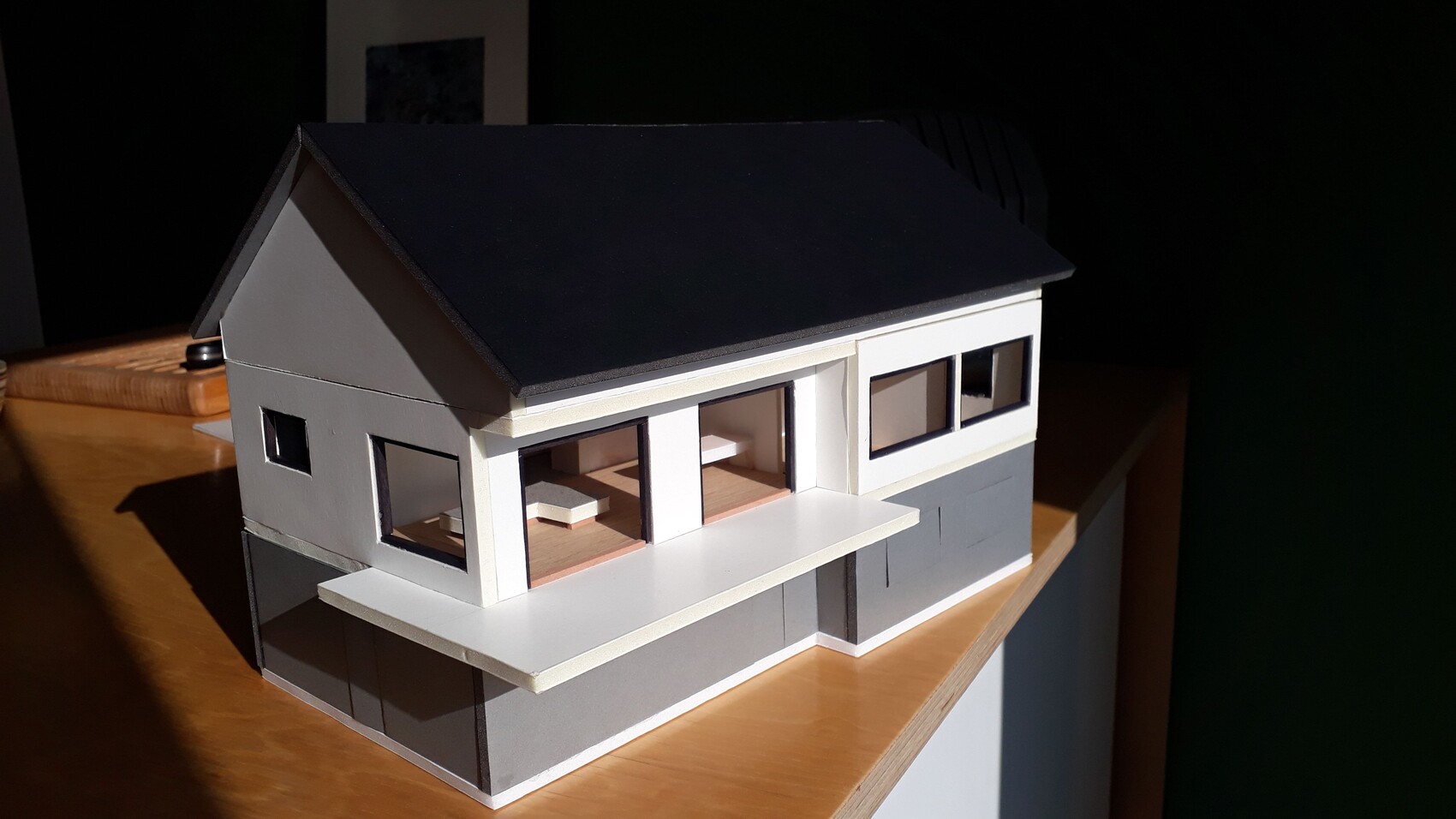 Modell eines modernen Hauses mit dunklem Satteldach und großen Fenstern.