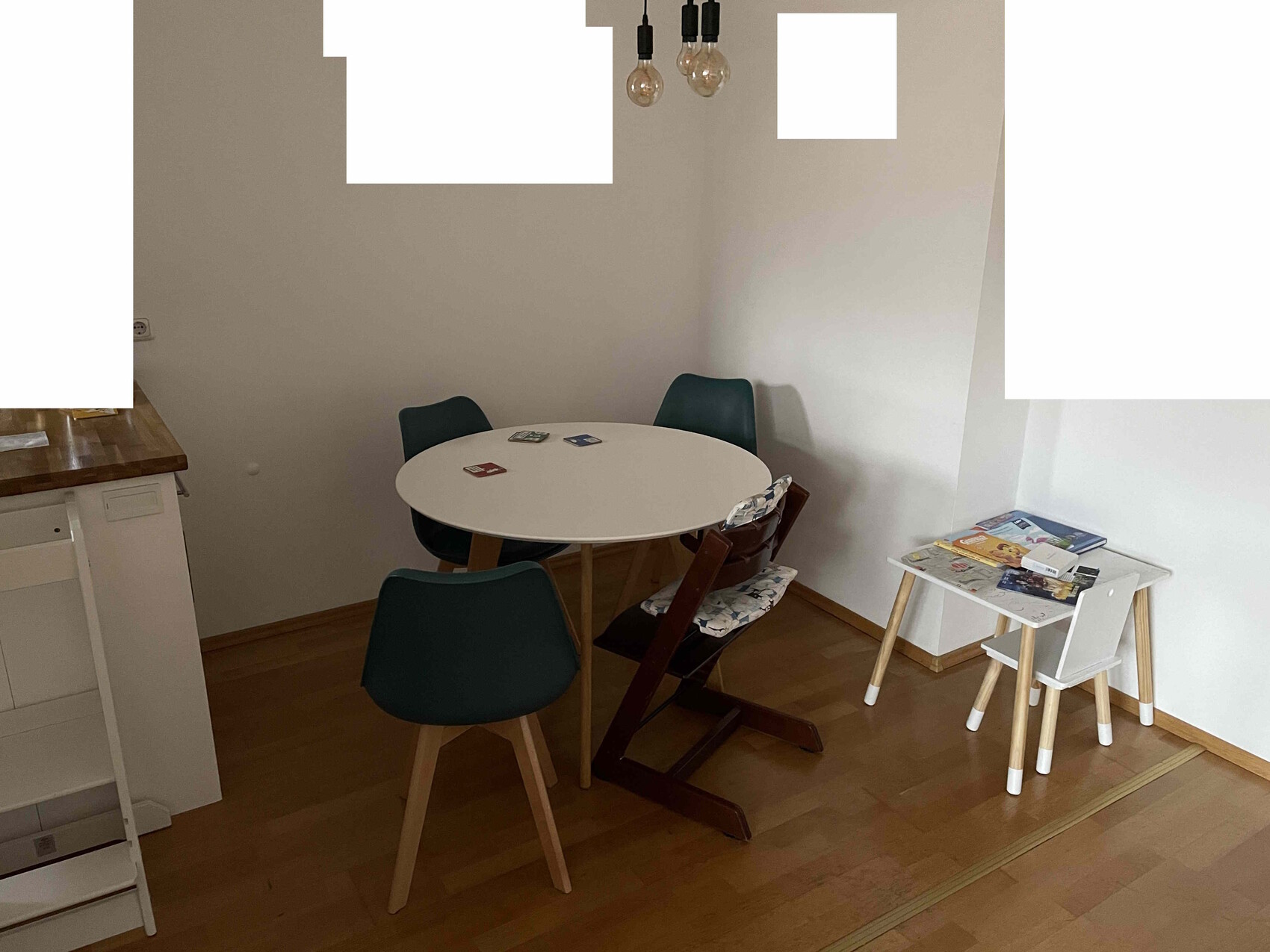Runder weißer Esstisch mit dunkelgrünen Stühlen, Hochstuhl, kleiner Kindertisch.