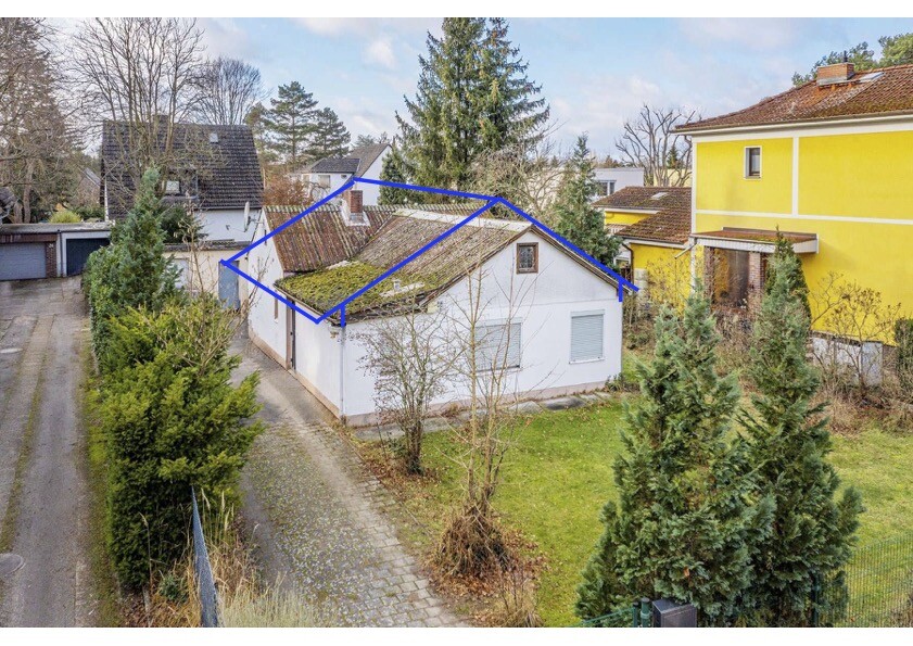 Vorderansicht eines kleinen weißen Hauses mit Dach, von Bäumen umgeben.